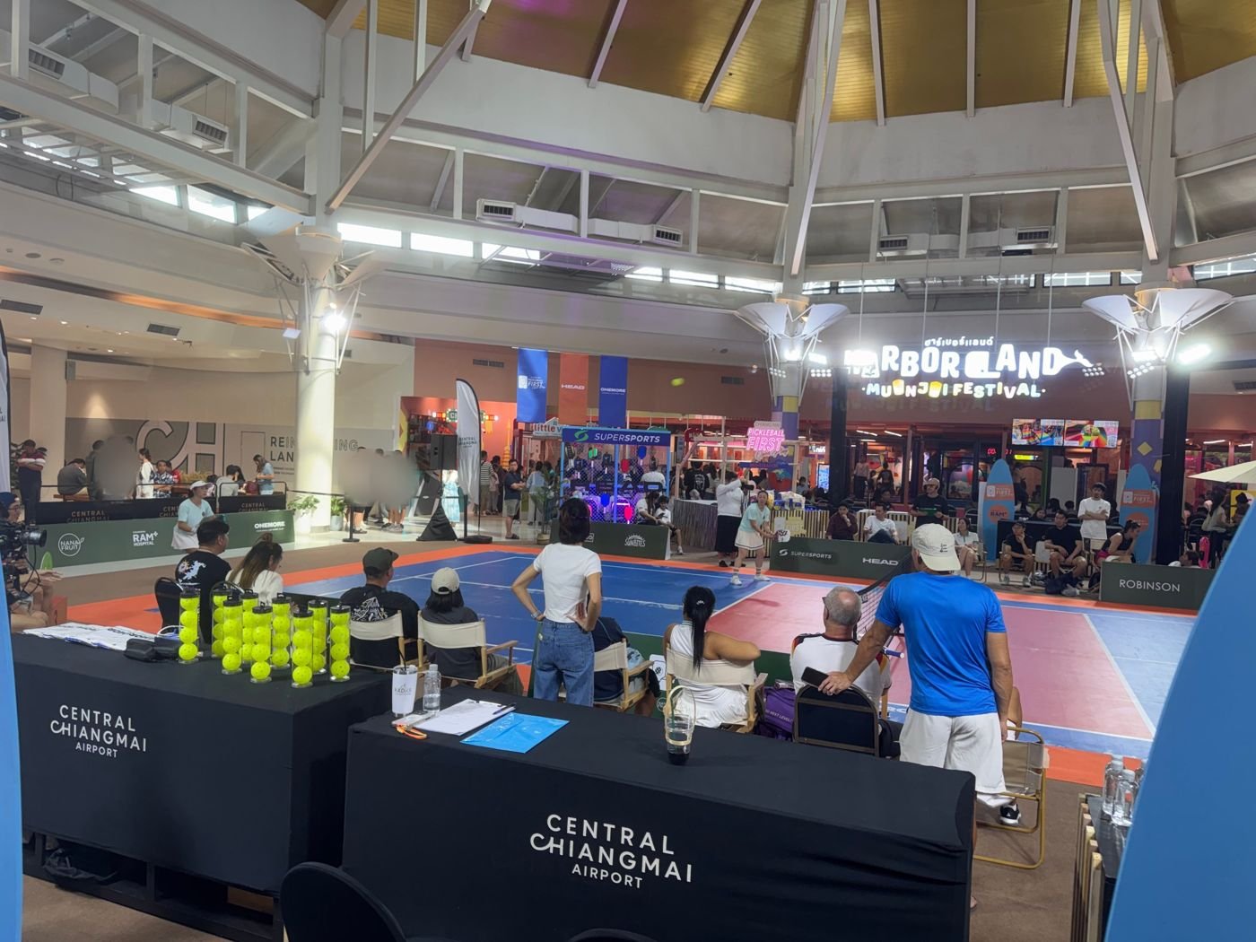 Spectators watching a match on the pickleball court in the Central Chiangmai Airport atrium, with the Supersports pro shop stand behind